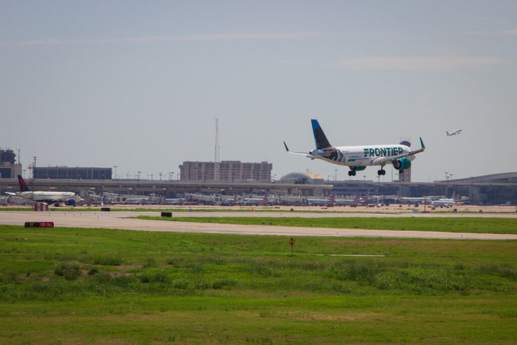 Plane landing with airport in background.