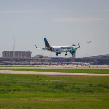 Plane landing with airport in background.